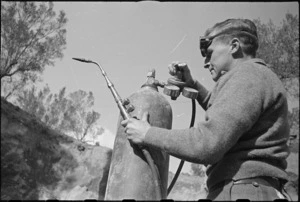 W A Boan adjusts pressure gauge on oxy acetone bottle at NZ Divisional Field Workshops, Cassino area, World War II - Photograph taken by George Kaye