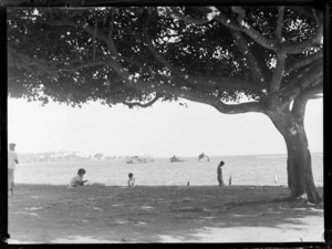 View of the remains of a sunken ship in Apia Harbour with unidentified locals on the beach in the foreground, Western Samoa