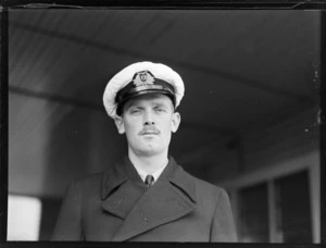 Portrait of Captain C A Merrington of Union Airways in front of a wooden building, Rongotai Airport, Wellington