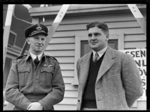 Portrait of (L to R) H E Boyes (RNZAF) in uniform and Max Turner of Union Airways, in front of a wooden building, Rongotai Airport, Wellington