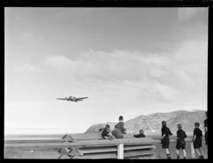 School boys watching a Lockheed Electra aircraft in flight over Rongotai airport, Wellington