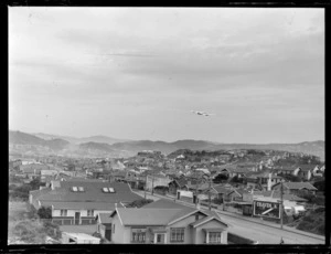 Lockheed Electra aircraft flying over houses, Lyall Bay, Wellington