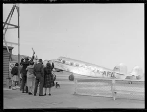 Group waving to Lockheed Electra aircraft, Rongotai airport, Wellington at it taxis off