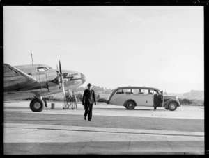 Pilot walking from Lockheed Lodestar aircraft 'Karoro' with Union Airways bus in background, Mangere airport, Auckland