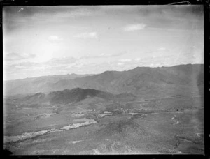 View of settlement in valley with forest covered mountains beyond, New Caledonia
