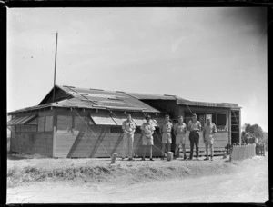 Tontouta Airfield and unidentified RNZAF personnel standing in front of a wooden building, New Caledonia
