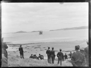 Group of unidentified RNZAF members watching rocket firing into sea from a hill, Ardmore Airport, Manurewa, Auckland