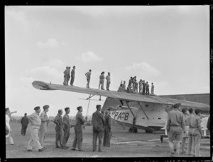 Airmen standing on the wing of a Catalina flying boat, watching an air display, at RNZAF Station, Hobsonville, Auckland