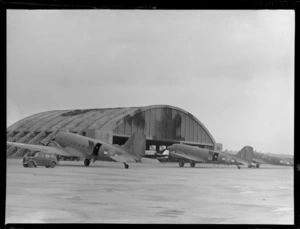 RNZAF Station, Whenuapai, Auckland, showing Douglas Dakota aeroplanes lined up on tarmac, and hangar