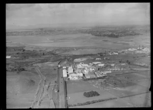View of Westfield Freezing Works with railway line and roads with the Manukau Harbour beyond, Penrose, Auckland