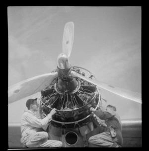 Close up view of two unidentified men working on a Pan American Airways Clipper Class Douglas Skymaster DC4 engine, on completion of 3rd survey flight, Whenuapai Airfield, Auckland