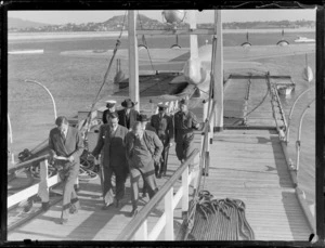 Lord Knollys and unidentified men boarding a Sunderland at Mechanics Bay, Auckland, includes a BOAC Hobart, Short Hythe flying boat in the background