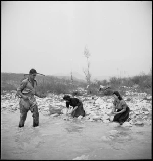 B A Nicholls demonstrates a knapsack sprayer to spray oils on the water at NZ Malarial School, Italy, World War II - Photograph taken by M D Elias
