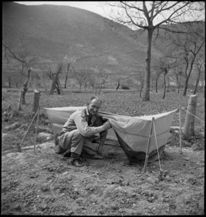 Staff Sergeant R R Rae showing mosquito-proof net to be issued to forward troops of 2 NZ Division in Italy, World War II - Photograph taken by M D Elias
