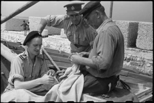 Lieutenant Colonel A L Noakes watches D Swan help skipper of Yugoslav cutter with sail repairs, Santo Spirito, Italy, World War II - Photograph taken by George Bull