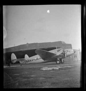Portrait of a Lockheed Lodestar aircraft, Karoro, ZK-A H X in front of the Union Airways of New Zealand Ltd hangar, Mangere, Auckland