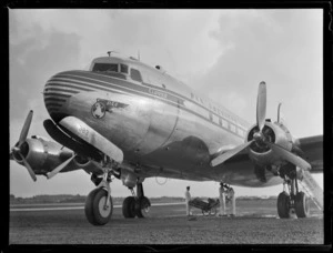 Nose view of PAA's Douglas Clipper DC4 passenger aircraft NC 88883 with ground personnel, [Whenuapai Airfield, Auckland?]