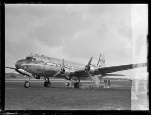 View of PAA's Douglas Clipper DC4 passenger aircraft NC 88883 and PAA's 5th Survey Group with ground personnel, [Whenuapai Airfield, Auckland?]