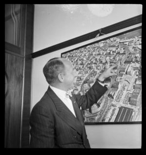 Ivy Lee Junior, PAA (Pan American Airways), pointing to a Whites Aviation photograph on the wall