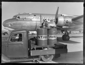 Vacuum Oil 'Intrava' truck, with barrels, including a Pan American Airways Clipper Mandarin aircraft, Whenuapai airfield, Auckland