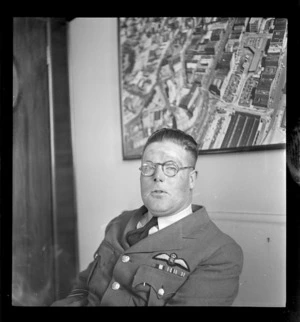 Portrait of Wing Commander, L P F Taylor, Air Department, with a Whites Aviation photograph on the wall behind