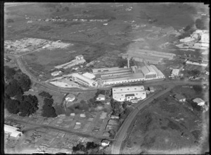View of the Fletcher Plywood Factory with stacked timber in foreground, Penrose, Auckland
