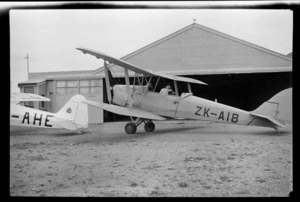 View of Auckland Aero Clubs' ZK-AIB Tiger Moth in front of a hangar, Mangere Airfield, Auckland