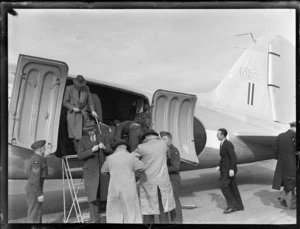 View of an RNZAF Dakota internal air transport plane with unidentified passengers arriving from [Paraparaumu?], Whenuapai Airfield, Auckland