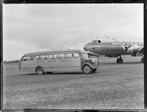 A Johnston's Airways Transport bus in front of a Pan American Airways Good Will Flights Clipper Cathay Class Douglas Skymaster DC4 passenger plane, Whenuapai Airfield, Auckland