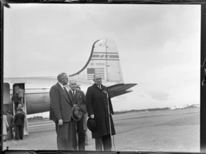 View of a Pan American Airways Good Will Flights Clipper Kathay DC4 passenger plane, with (L to R) Col Shaw and J A C [Allum?] in front with an unidentified man in between, Whenuapai Airfield, Auckland