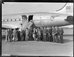View of Pan American Airways Good Will Flights No2 of Clipper Class Kathay DC4 passenger plane, with an unidentified group of people in front, Whenuapai Airfield, Auckland