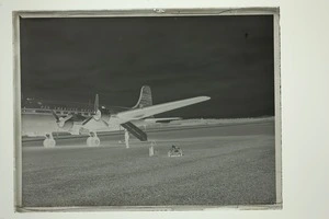 View of a Pan American Airways Good Will Flight Clipper Cathay Class Douglas Skymaster DC4 passenger plane with an unidentified man in front, Whenuapai Airfield, Auckland