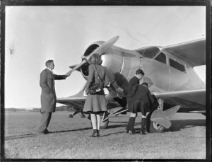 Auckland Aero Club, Mangere, Auckland, showing a group of unidentified people standing in front of a Beechcroft aircraft, checking out the propellor and wheels of the aircraft