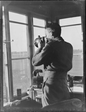 Portrait of an unidentified man operating aircraft signal equipment in the Mangere Control Tower, Auckland