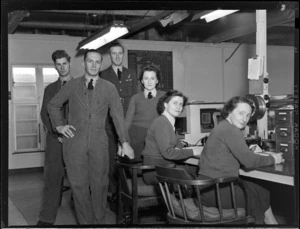 Flying Control Room, Mechanics Bay, Auckland, showing a group of unidentified people, three men standing with one of the women and the other two women sitting at the desk