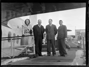 British Oversea's Airways Corporation's Mrs Wallen on the gangway ramp with Messrs G Roberts, [E A R?] and Leo White, standing next to a flying boat aircraft, Mechanics Bay, Auckland