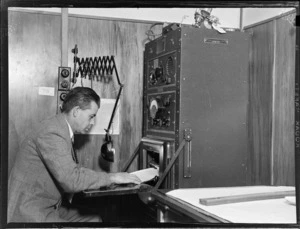 View of unidentified man reviewing data at a machine, Meteorological Section, Mechanics Bay, Auckland City