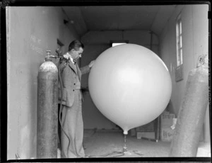 View of an unidentified man filling a weather balloon, Meteorological Section, Mechanics Bay, Auckland City