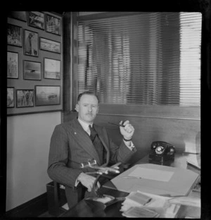Portrait of E A Robinson holding a pipe, Whites Aviation Office, Auckland City