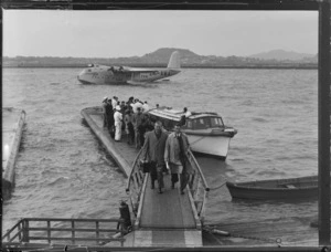 Arrival of unidentified passengers and crew disembarking from a launch off TEAL Short Tasman Flying Boat ZK-AMA 'Australia' at Mechanic's Bay, Auckland City