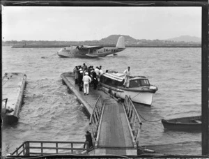 Arrival of TEAL Short Tasman Flying Boat ZK-AMA 'Australia' with unidentified passengers and crew disembarking a launch onto a floating dock, Mechanic's Bay, Auckland Harbour