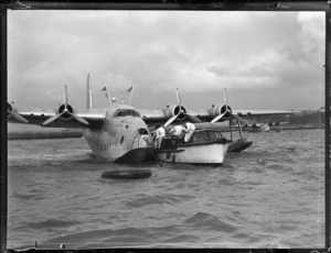 TEAL Short Tasman Flying Boat 'Australia' being hitched to a launch with a mooring line by unidentified crew, Mechanic's Bay, Auckland Harbour
