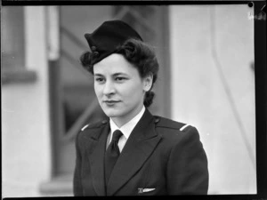 Portrait of Miss J Paterson TEAL Stewardess in uniform outside an unidentified building, [Auckland?]