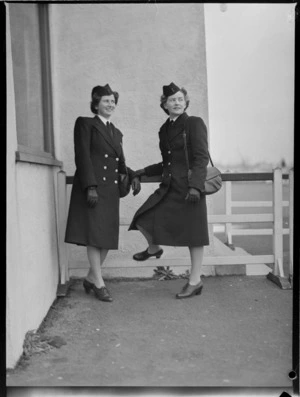 Portrait of Miss B P Morton and Miss L M Magnus, TEAL Stewardesses in uniform outside an unidentified building, Mechanic's Bay, Auckland City
