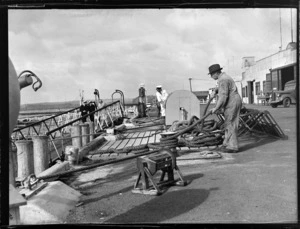 View of an unidentified TEAL employees with ropes mooring TEAL Short Empire Flying Boat ZK-AMA 'Awarua' to Mechanic's Bay wharf, Auckland Harbour