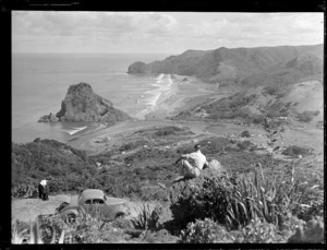 Unidentified individuals at Piha, Auckland, includes view of beach, farmland and Lion Rock