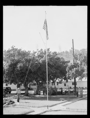 Sailor raising the American flag, as other military personnel stand to attention, Ile Nou, New Caledonia