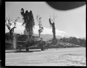 View from a forest airfield, with a twin engine military transport plane [IS- 327?] in foreground, to the erupting volcano of Mount Bagana beyond, Bougainville Island, North Solomon Island group