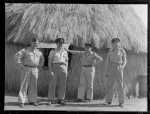Royal New Zealand Air Force crew, standing in front of a native hut, Rarotonga, showing (l to r): Flight Lieutenant Chapman, W R A [Kinleif?], Flight Lieutenant Fowler, First Officer F Meyer