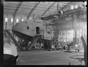 Side and nose view of a Short Tasman aircraft, in a workshop, Hobsonville, Auckland, including scaffolding